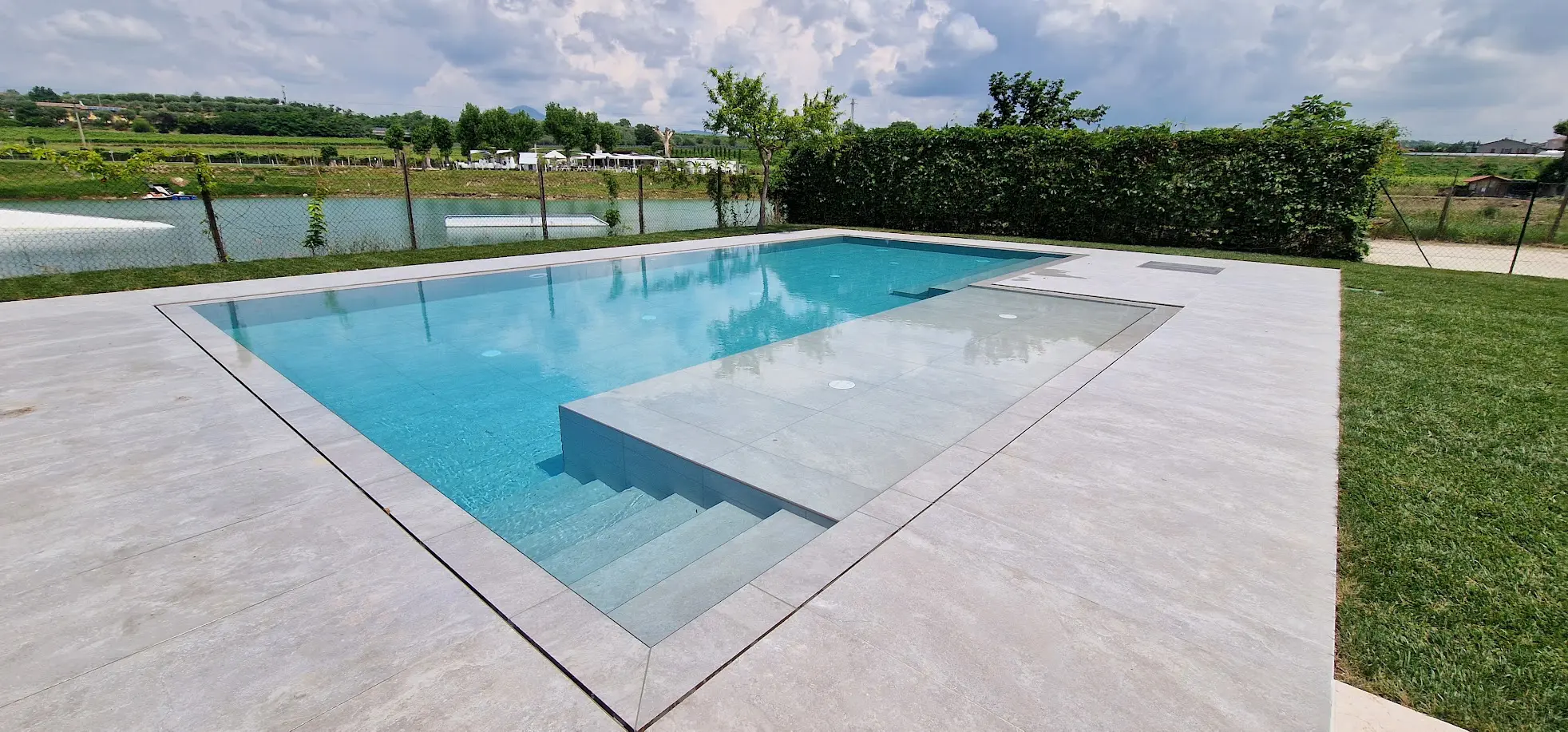 Piscina moderna con bordo in pietra, vista esterna.